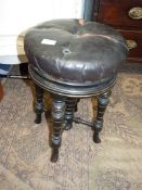 A circular leatherette/rexene upholstered circular Piano Stool standing on a base with four turned