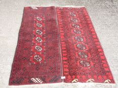 Two small red and black ground bordered and patterned rugs, 58 1/2'' long x 19 1/2'' wide approx.