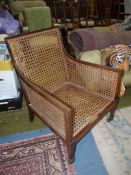 An Edwardian Mahogany framed armchair having caned sides and back standing on tapering square legs