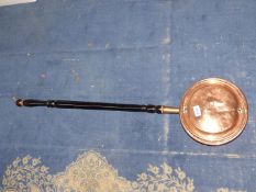 A copper warming pan having wooden handle.
