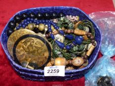 A blue raffia box and contents of costume beads, necklaces, Stratton compact etc.