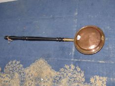 A copper warming pan having wooden handle.