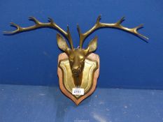 A mounted brass model of stag's head on wooden plinth.