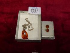 An amber pendant on 925 mounting and chain with a pair of amber stud earrings by John McKellar.