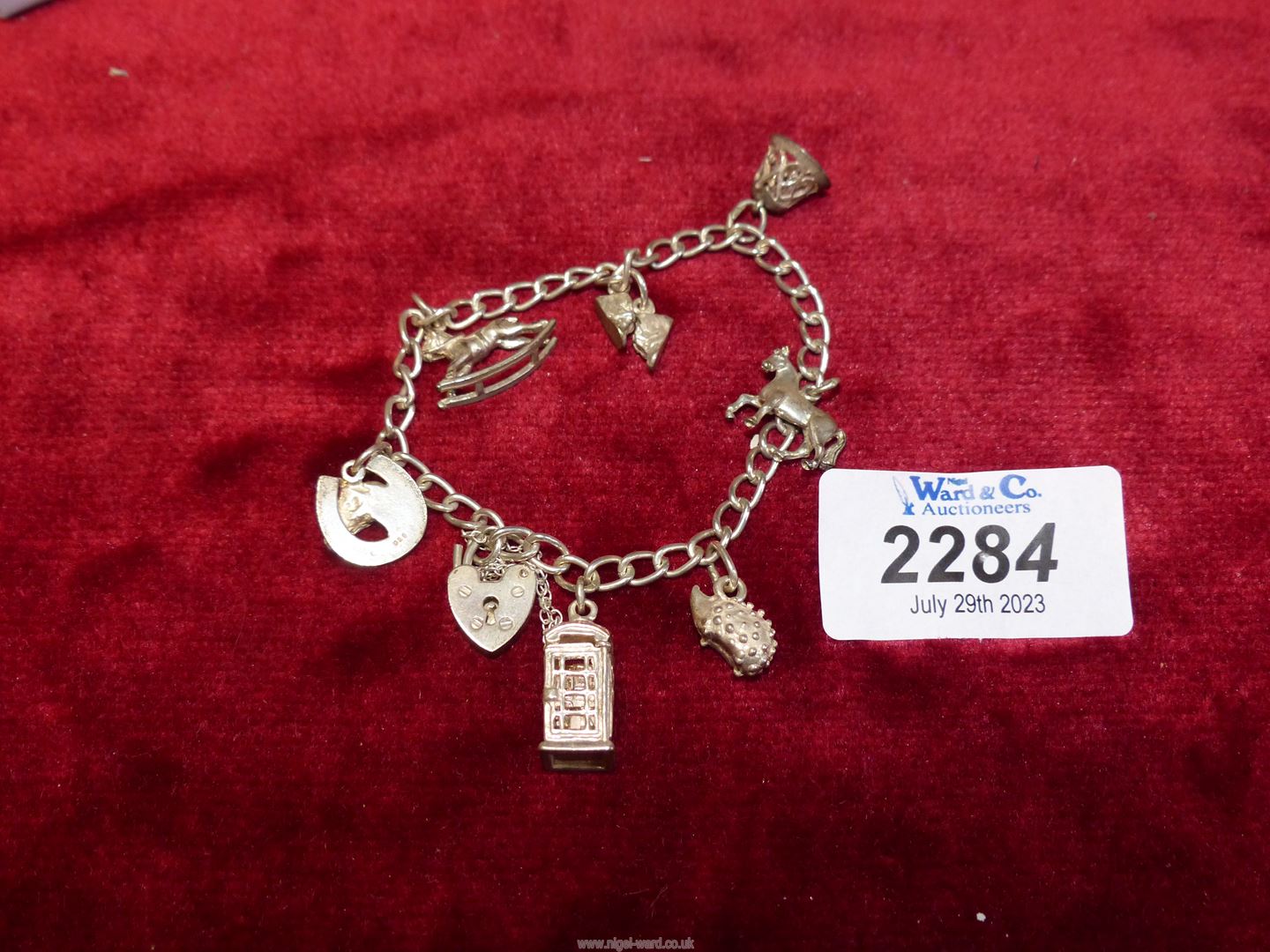 A silver charm bracelet with heart padlock clasp, charms including telephone kiosk, hedgehog, bell, - Image 2 of 2