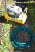 A working Stanley eight-bar 15Hp, 24 litre Compressor, and a roll of green garden hose.