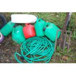 Green garden hose and a selection of fuel cans.