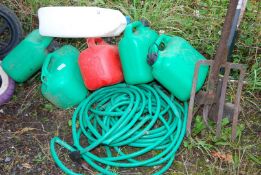 Green garden hose and a selection of fuel cans.