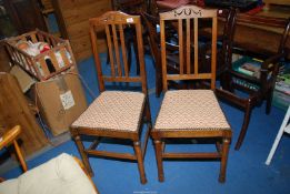 A pair of dining chairs with tapestry style upholstered seats.