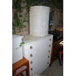 A white five drawer chest and a Lloyd Loom style laundry bin.