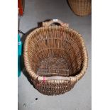 A large wicker log basket with wooden handles.