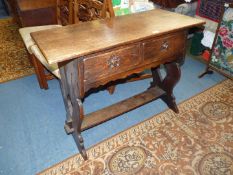 An Oak Arts and Crafts Side Table having a pair of shaped front frieze drawers and standing on