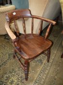 An Elm seated Captain's Chair having turned arm supports, legs and stretchers.