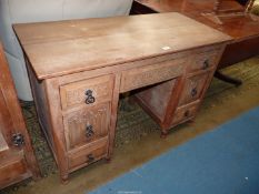 A light Oak Kneehole Dressing Table having scroll and foliage and linen fold details to the drawer