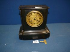 A small black slate Mantle clock having brass coloured face, Roman numerals, two chimes,