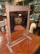 A light Oak Swing Mirror with a scroll carved top rail and raised on turned supports,