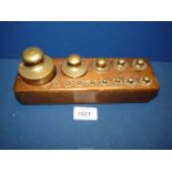 A set of small brass laboratory balance scales weights in the original wooden block stand.