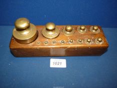A set of small brass laboratory balance scales weights in the original wooden block stand.
