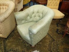 An early 20th century button back Tub shaped Armchair having turned front feet and upholstered in