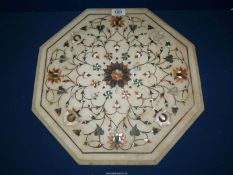 A heavy octagonal stone table top skilfully and beautifully inlaid with trailing flowering stems in