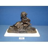 A Bronze figure of a child reading a book on a white marble base,