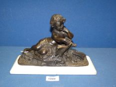 A Bronze figure of a child reading a book on a white marble base,