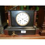 A black slate Mantle clock with red details, having white enamel face, Roman numerals, two chimes,