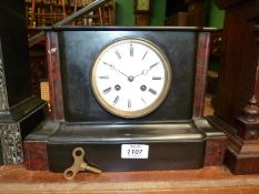 A black slate Mantle clock with red details, having white enamel face, Roman numerals, two chimes,