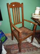 An Oak framed open armed Elbow Chair having a relief patterned leather seat,
