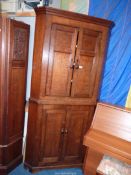 A full height Georgian Oak Corner Cupboard having two pairs of recessed panelled doors with turned