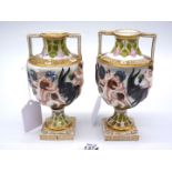 A pair of urn shaped Capo di Monte style Cherub vases with gilt colour square bases and raised