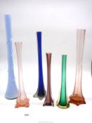 A quantity of coloured single stem vases in blue, pink and green.