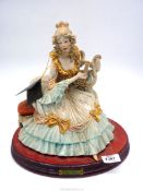 A porcelain figure of a lady in period dress playing a harp, 12 1/2" wide x 12" tall.
