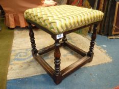 An old Oak framed Stool having turned legs united by perimeter stretchers and with an over-stuffed