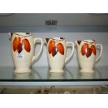 Three graduated 'Autumn leaves' jugs, (small chips to rims), by Clarice Cliff for J. Wilkinson Art.