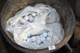 A large quantity of golf balls in a plastic dustbin.