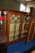 An Edwardian display cabinet with shelves, standing on tapering square legs,