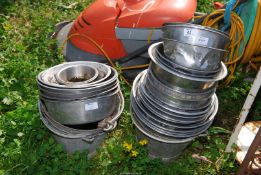 A quantity stainless steel dog bowls, and three galvanised buckets.