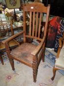 An Oak framed open armed Elbow Chair having a relief patterned leather seat,