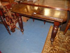 An Edwardian Mahogany windout Dining Table standing on turned and reeded legs terminating with