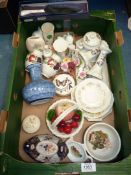 A box of china including a white basket with an apple and cherries and two candlesticks with floral