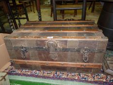 A wooden steamer trunk with metal bands and fastenings and leather handles,