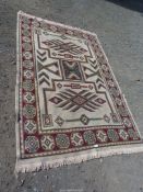 A bordered, patterned and fringed woven rug, burgundy ground border, cream central ground,