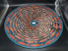 A large blue glass platter decorated with shoal of copper coloured fish, 26 3/4" diameter.