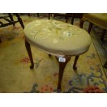 An oval Stool standing on cabriole legs terminating in scroll feet,