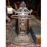 A cast iron umbrella/stick stand depicting Putti carrying platter of fruit atop their heads to the