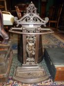 A cast iron umbrella/stick stand depicting Putti carrying platter of fruit atop their heads to the