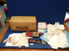 A basket of linens including lace collars, handkerchieves etc.