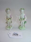 A pair of Derby porcelain Putti figures holding baskets of flowers (a/f) 4" tall.