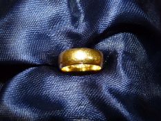 A 22ct gold wide Wedding band, smaller than a K size, weight 6.9g.